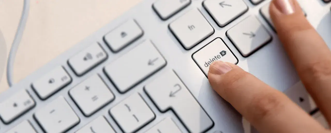 Palec naciska klawisz "delete", symbolizując decyzję jak usunąć konto na Facebooku.