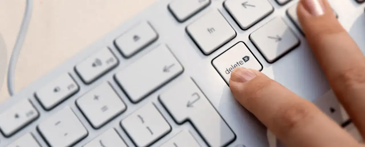 Palec naciska klawisz "delete", symbolizując decyzję jak usunąć konto na Facebooku.